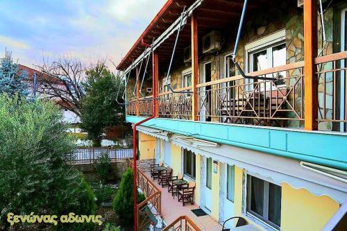 un edificio con balcone e sedie sopra di Guesthouse Adonis a Kato Loutraki