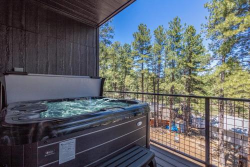 a hot tub on a balcony with a view of trees at Le Cabin Noir Modern Alpine Retreat Spa BBQ in Flagstaff
