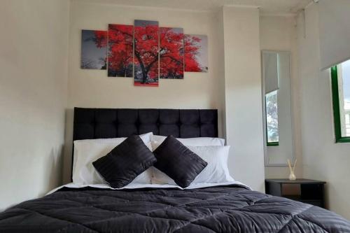 een slaapkamer met een bed met twee schilderijen aan de muur bij Luminoso y confortable apartamento a 6 min aeropuerto in Bogota