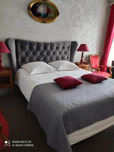 a bedroom with a large bed with red pillows at Manoir La Haie Chapeau in Saint-Thurial