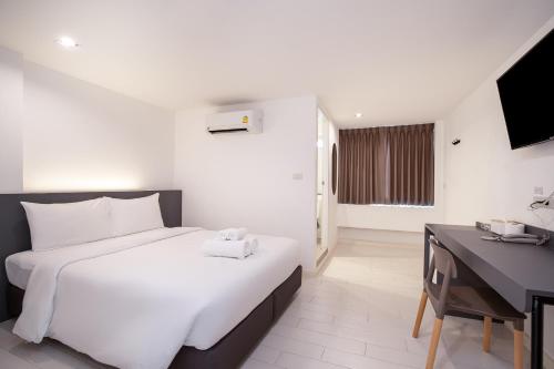 a bedroom with a large white bed and a desk at The Urban Oasis in Bangkok