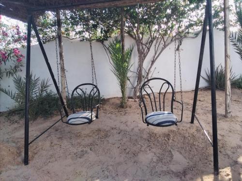 two swings in front of a white wall at Dar Aladin in Arkou