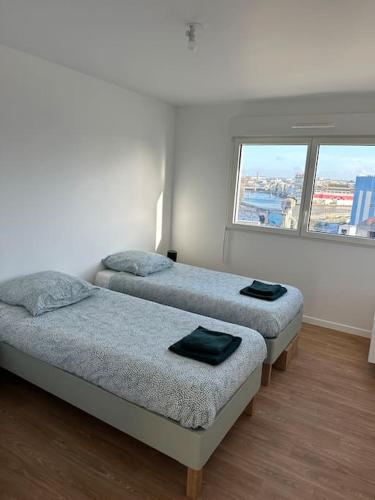 deux lits dans une chambre avec deux fenêtres dans l'établissement Appartement spacieux doté d'une grande terrasse, proche Paris. Parking gratuit, à Ivry-sur-Seine