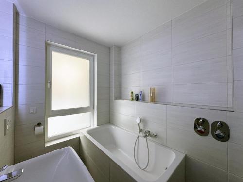 een witte badkamer met een bad en een raam bij Appartement Neugasse de Luxe in Bad Camberg