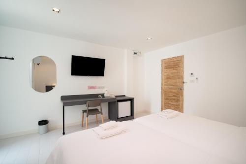 a white room with two beds and a desk at The Urban Oasis in Bangkok