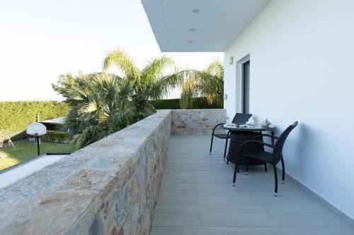 a patio with a stone wall and a table with a laptop at Villa Aggeliki in Agioi Theodoroi