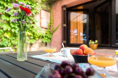 une table avec un vase de fleurs et un bol de fruits dans l'établissement Pavillon Saint Clair la campagne au bord de l eau et 2 velos, à Sète