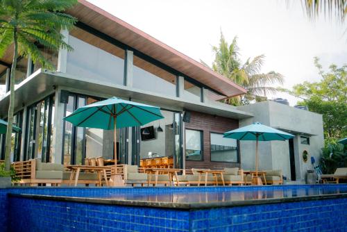 a house with tables and umbrellas next to a pool at Sayana Bali Resto & Bar in Gianyar