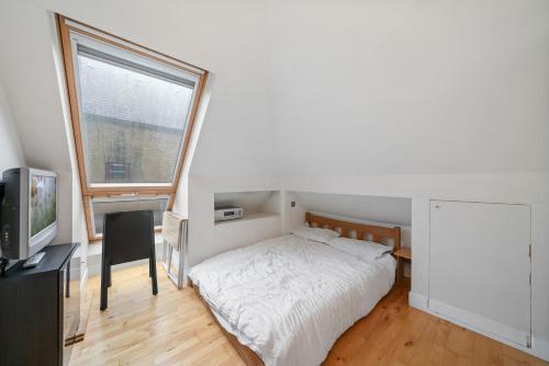 a bedroom with a bed and a desk and a window at Glamorous 2BR House, Outdoor Space & Free Parking in London