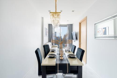 a dining room table with black chairs and a chandelier at The Echelon Sukhumvit 11 by LeFoyer in Bangkok