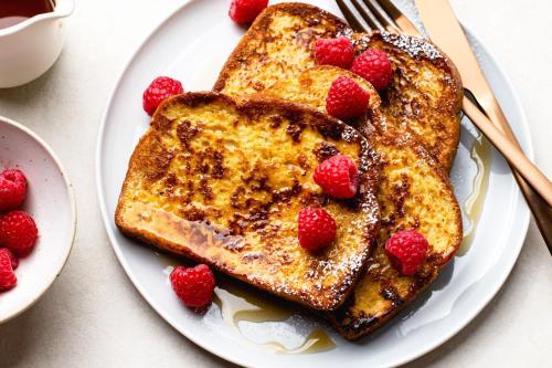 a plate with two pieces of french toast with raspberries at Niagara Riverview Closest to Falls, Free Breakfast Delivered Daily in Niagara Falls
