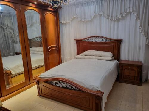een slaapkamer met een houten bed en een spiegel bij Cairo city Rooms in Nasr city in Caïro