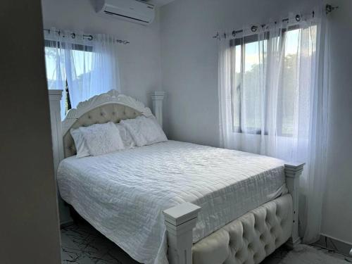 een wit bed in een witte slaapkamer met ramen bij Espectacular Villa En Alquiler in Las Terrenas