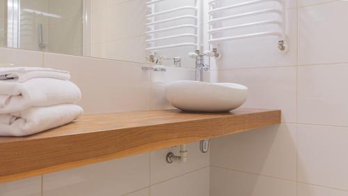 a bathroom with a sink and towels on a shelf at VacationClub - STUBAI Apartament 19 in Sienna