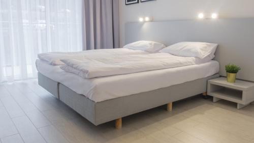 uma cama com lençóis brancos e almofadas num quarto em VacationClub - STUBAI Apartament 19 em Sienna