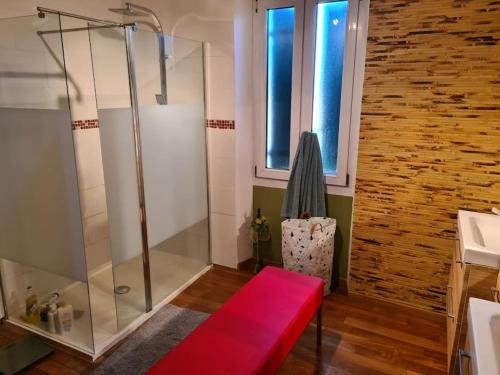 La salle de bains est pourvue d'une douche et d'un banc rouge. dans l'établissement Belle maison avec piscine, à Le Val