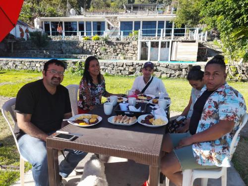 un grupo de personas sentadas alrededor de una mesa comiendo comida en Hotel Porto Bello en San Pedro La Laguna