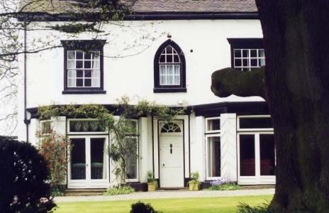 a white house with black windows and a door at Abbot's Haye in Cheadle
