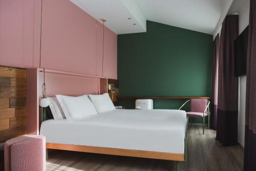 1 dormitorio con cama blanca y pared verde en Al Ponticello, en Comacchio