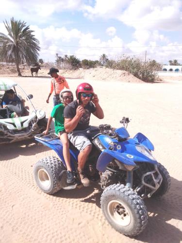 a man and a boy on a four wheeler on the beach at Dar Aladin in Arkou