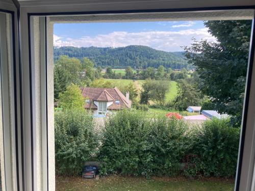 a window with a view of a house in a field at Wohnresidenz Casa Fortuna in Suhr