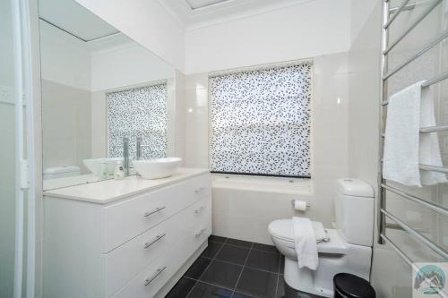 Baño blanco con aseo y lavamanos en Aircabin - Beecroft - Sydney - 3 Bed Holiday House, en Beecroft