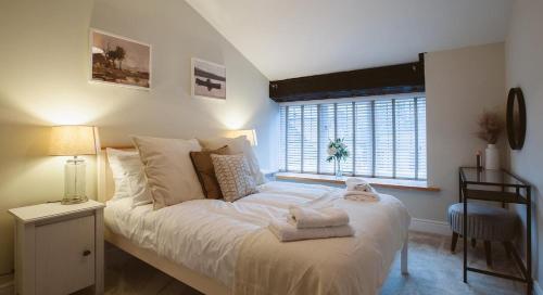 sypialnia z łóżkiem z białą pościelą i oknem w obiekcie Gardener's Cottage w mieście Chepstow