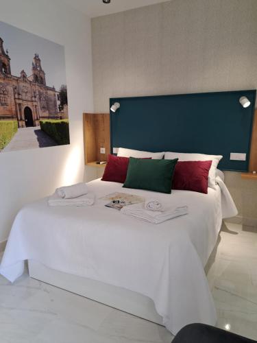 a bedroom with a large white bed with red and green pillows at VIVAL RASTRO DELUXE in Úbeda