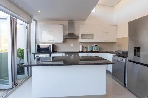 a kitchen with white cabinets and a black counter top at Victoria Views in Cape Town