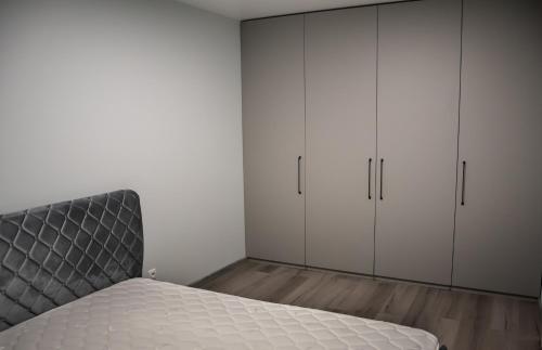 a bedroom with white cabinets and a gray bed at Jaukus butas Šiaulių centre in Šiauliai