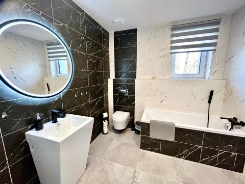 a bathroom with a sink and a tub and a mirror at Apartmány PREMIUM se soukromým parkováním in Česká Lípa