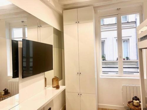 un salon avec une télévision à écran plat sur un mur dans l'établissement Studio Annah, à Paris