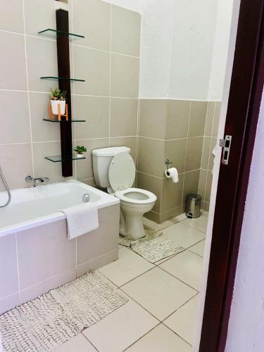 a bathroom with a toilet and a bath tub at 82 St Andrews Jackal Creek Golf Estate with Backup power & Golf course views in Roodepoort