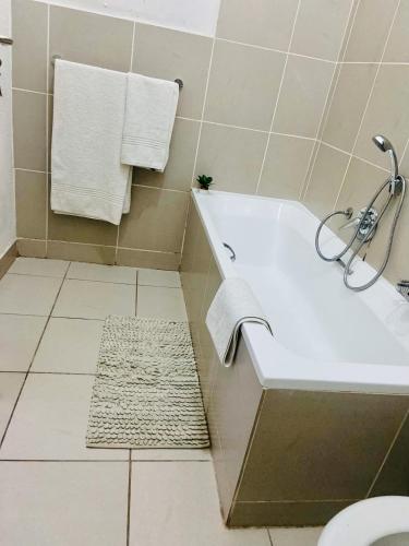 a bathroom with a white bath tub and a rug at 82 St Andrews Jackal Creek Golf Estate with Backup power & Golf course views in Roodepoort