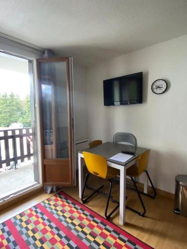 Zimmer mit einem Tisch, 2 Stühlen und einem Fenster in der Unterkunft Studio au pied des pistes. in Ax-les-Thermes