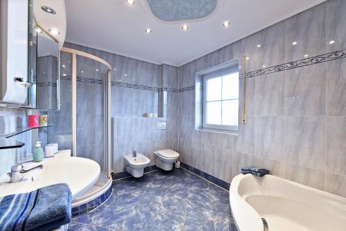 a bathroom with a tub and a sink and a toilet at Elegante Ferienwohnung Relax in Prien am Chiemsee