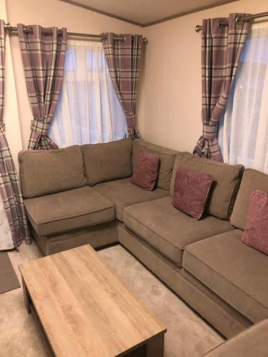 a brown couch in a living room with curtains at Lovely Caravan in Turnberry