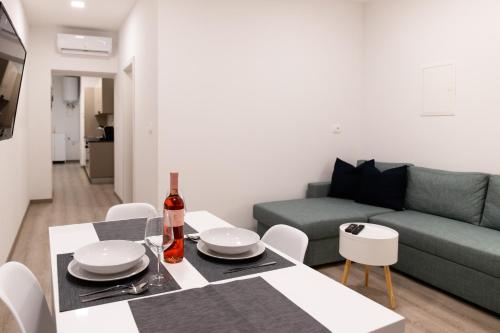ein Wohnzimmer mit einem Tisch und einem grünen Sofa in der Unterkunft Oliver street apartment Vipava in Vipava
