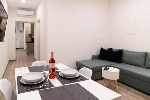a living room with a table and a green couch at Oliver street apartment Vipava - 50m from city center in Vipava