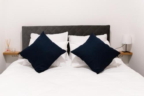 a bed with black and white pillows on it at Oliver street apartment Vipava - 50m from city center in Vipava