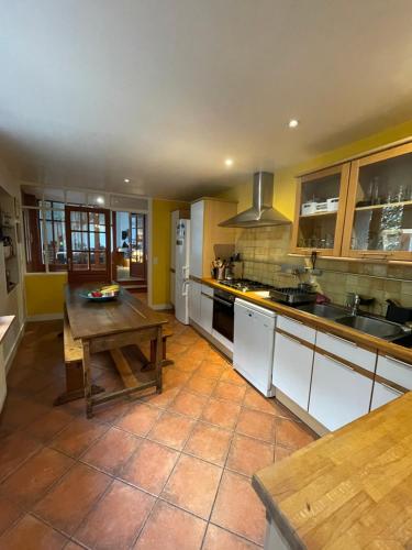 une grande cuisine avec une table en bois. dans l'établissement Large house near Paris, ideal OG, à Colombes