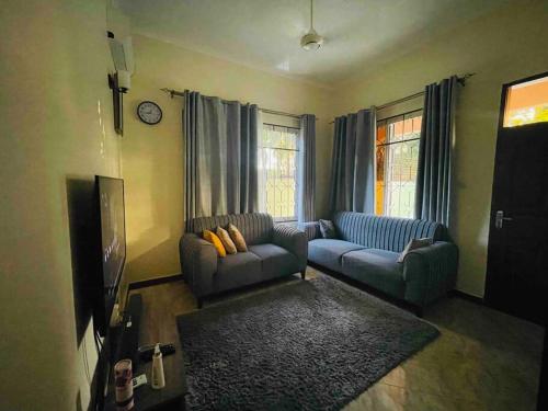 a living room with two couches and a tv at 1 Bed Cozy Apartment Free Wi-Fi Netflix Hot Shower in Dar es Salaam