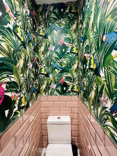 a bathroom with a toilet and a mural of plants at Social Central - No 1 for large groups in Cardiff
