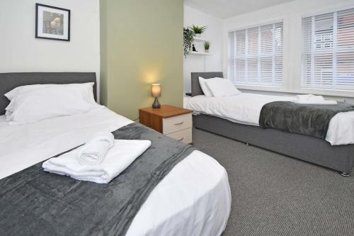 Un dormitorio con dos camas con toallas blancas encima. en Croft House - By Sigma Stays, en Crewe