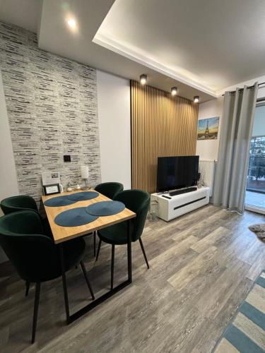 Apartament Kamila Ostróda في أوسترودا: غرفة معيشة مع طاولة وكراسي وتلفزيون