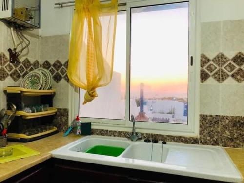uma cozinha com um grande lavatório branco e uma janela em Résidence Aquilaria Dar Nouha em El Haouaria