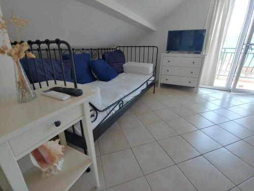 a bedroom with a bed with blue pillows and a tv at Apartment Kumbor in Herceg-Novi