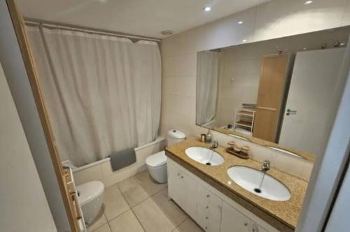 a bathroom with two sinks and a toilet and a mirror at Apartamento completo con piscina terraza vistas del mar in Badalona