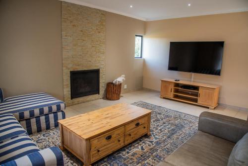 uma sala de estar com uma televisão de ecrã plano e uma mesa de centro em 137 Vaal De Grace Golf Estate em Parys