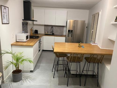 une cuisine avec des armoires blanches et un comptoir en bois dans l'établissement Maison Bollène, à Bollène